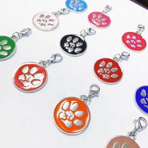 Detailed close-up of round zinc alloy pet ID tags with colorful paw prints and lobster clasps