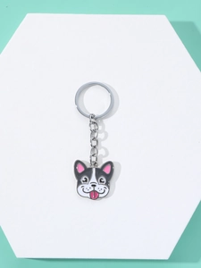 Close-up of a cartoon French Bulldog enamel keychain with silver chain on a white platform