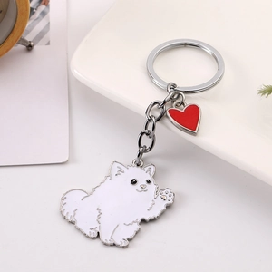 Détail d'un porte-clés chien Poméranien blanc avec un pendentif coeur rouge vif