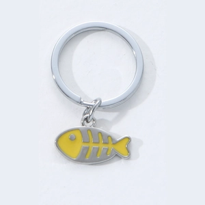 Macro detail of silver zinc alloy flat key ring with a vibrant yellow fishbone charm