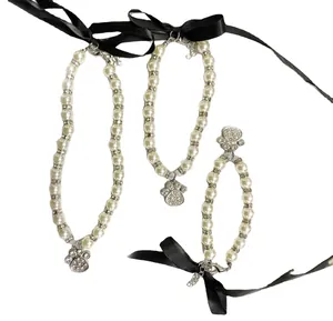 Detailed view of white pearl pet necklaces featuring crystal paw pendants and black bows