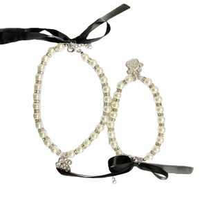 Detail of pet pearl necklace with crystal paw charm and elegant black ribbon bow