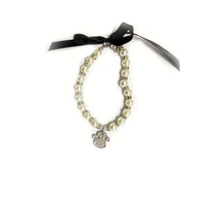 Detailed close-up of pet pearl necklace with rhinestone paw pendant and black ribbon bow