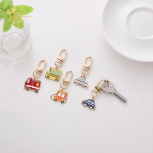 Flat lay of colorful enamel vehicle keychains including fire truck and school bus