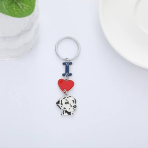 Detail of dalmatian dog keychain with red heart and blue letter charm on white surface