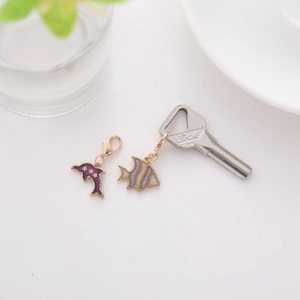 Close-up of purple dolphin and tropical fish charms with golden lobster clasp and key