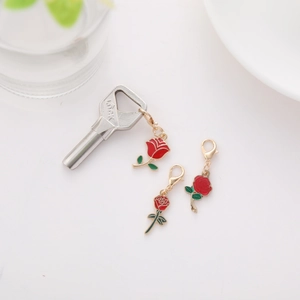 Detail of red enamel rose charms with golden edges and lobster clasps for keychains