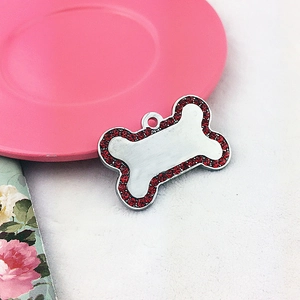 Detail of bone-shaped pet tag with red rhinestones and polished metal surface