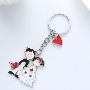 Detail of cartoon bride and groom metal keychain with red heart charm for wedding gifts