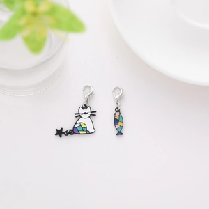 Detail of cartoon cat and fish enamel pendant charms with silver lobster clasps