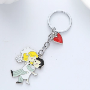 Gros plan sur un porte-clés de couple de mariés en métal avec un pendentif cœur rouge