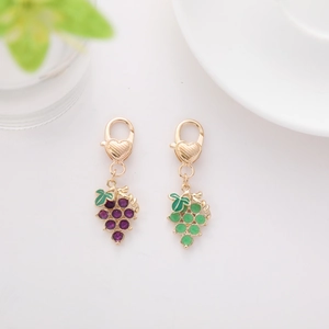Detail of purple and green grape keychains with golden heart-shaped lobster clasps