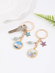 Detail of a gold alloy ocean keychain with starfish, seashells, and beach resin charms