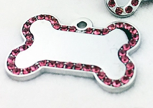 Macro shot of bone-shaped stainless steel pet ID tag with sparkling pink rhinestones