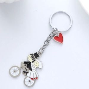 Detail of cartoon wedding couple on bicycle keychain with red heart and silver ring