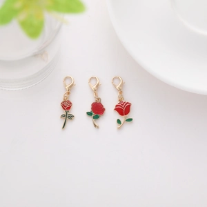 Three red enamel rose keychain pendants with gold lobster clasps and green leaves