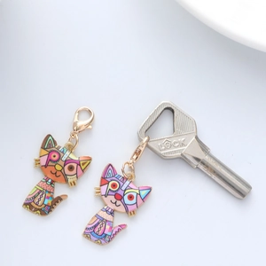 Detail of colorful pop art cat charms with geometric patterns and golden lobster clasp