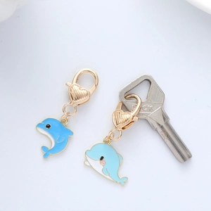 Detail view of blue dolphin enamel pendants with golden heart lobster clasps on a key