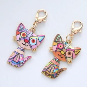 Detailed macro view of colorful geometric enamel cat charms with golden lobster clasps