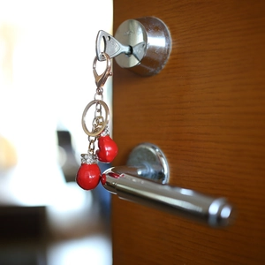 Detail of red boxing glove keychains with rhinestones hanging on a wooden door lock