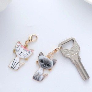 Close-up of cute cartoon white cat and realistic grey cat charms with golden lobster clasps