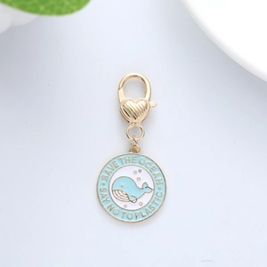 Detail of Save The Ocean enamel charm with whale illustration and gold lobster clasp