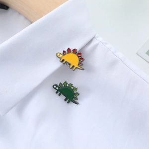 Broches dinosaures mignonnes en émail jaune et vert épinglées sur un col de chemise blanche