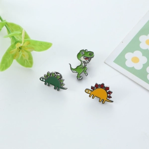 Lot de trois pin's émaillés colorés comprenant un T-Rex vert et un stégosaure orange