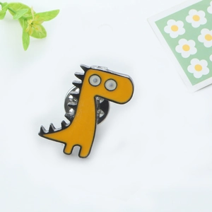Détails d'une broche dinosaure en émail jaune avec fermoir papillon sur fond blanc épuré