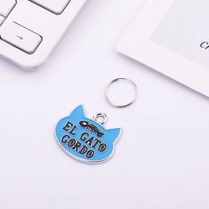 Macro detail of sky blue cat head pet tag with fishbone pattern and engraved text