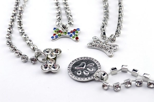 Detailed close-up of pet necklaces with crystal bone charms and silver chain finishes