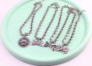Detail of crystal bone and paw print pet necklaces on a mint green display tray