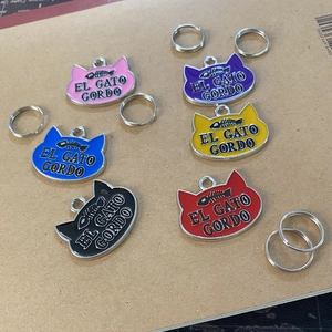 Detailed close-up of colorful cat head shaped metal pet ID tags with fishbone pattern
