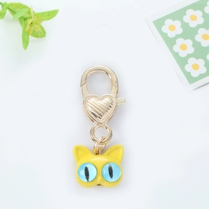 Detailed close-up of a golden cat keychain with blue eyes and heart shaped lobster clasp