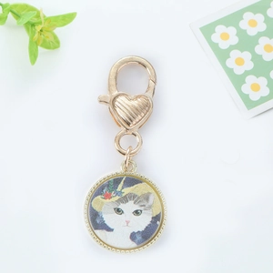 Detailed close-up of a golden cat pendant keychain with a vintage floral cat illustration