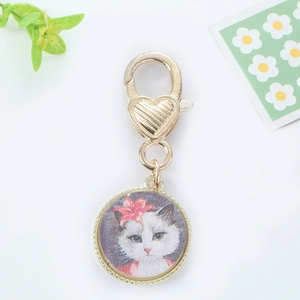 Close-up of a golden cat illustration pendant with a heart-shaped lobster clasp