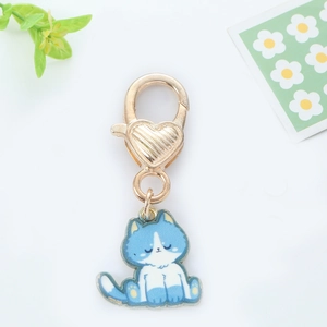 Detail of blue and white cat enamel pendant with golden heart-shaped lobster clasp hook