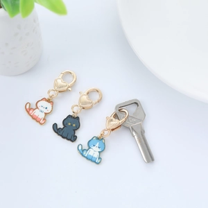 Close-up of three colorful cat enamel pendants with golden heart lobster clasps