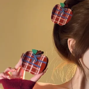 Close-up of apple-shaped plaid hair claw clip with blue bow and leaf detail on hair
