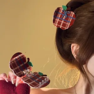 Detail view of a vintage red plaid apple-shaped hair claw clip worn on braided hair