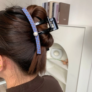 Large black claw clip with blue checkerboard pattern and pearl detail on bun hair