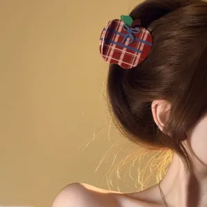 Close-up of a red plaid apple hair claw with a blue bow detail in a stylish ponytail