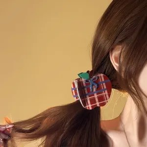 Detail view of red plaid apple hair claw clip with blue bow tie worn on hair