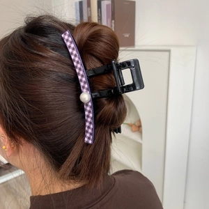 Close-up of a purple gingham hair claw clip with a large pearl detail on model hair