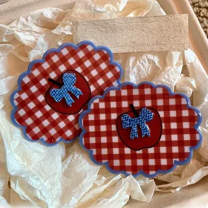 Detailed close-up of red gingham hair clips with apple and bow motifs in packaging