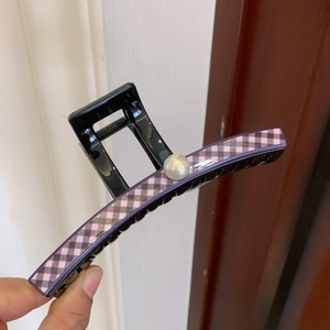 Detail of large black PVC hair claw clip featuring pink check pattern and pearl accent