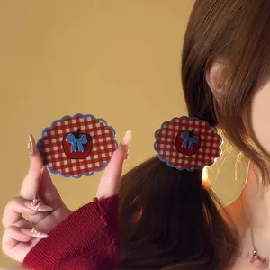 Detail showing vintage red plaid claw clip with apple motif and blue bow decoration