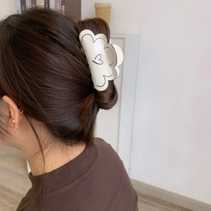 Détail d'une pince à cheveux en PVC crème avec motifs de cœur sur un chignon élégant