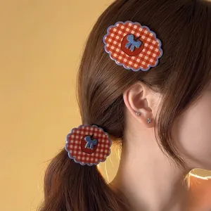 Vintage red plaid hair claw clip with blue bow design shown on a ponytail hairstyle