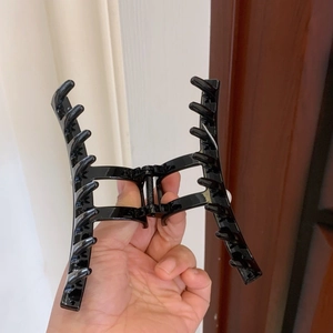 Detailed view of large glossy black hair claw clip with ten-tooth design for long hair